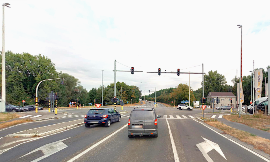 Drie auto's wachten voor rood licht bij een kruispunt met verkeerslichten en pijlen op de weg. (vergroot foto)